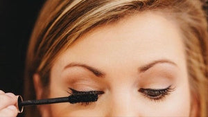 Person applying mascara to their eyelashes with a brush.
